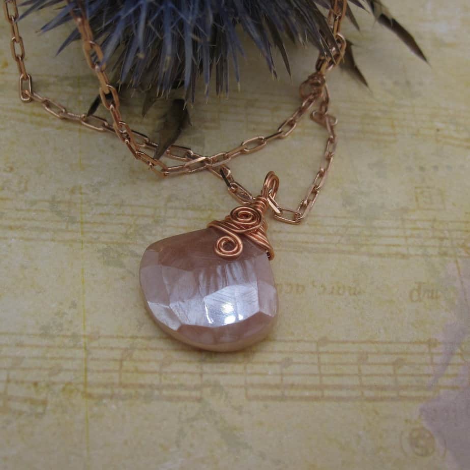Pendant with tear drop shaped facet cut peach moonstone. With rose gold plated wire spiral and rose gold plated chain.